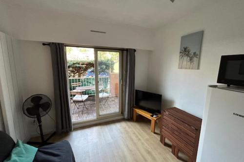 d'un salon avec une télévision et une porte coulissante en verre. dans l'établissement Apartment 20 m from the sea - Cavalaire-sur-Mer, à Cavalaire-sur-Mer