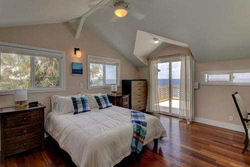 a bedroom with a bed and two windows at Paradise Ocean View in Keaau