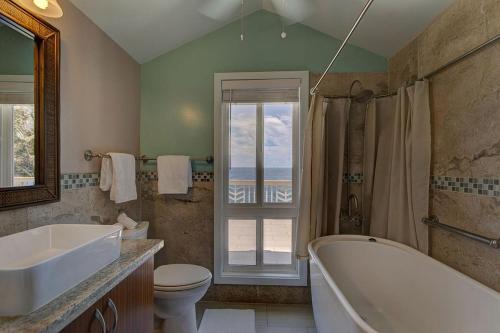 a bathroom with a tub and a toilet and a sink at Paradise Ocean View in Keaau