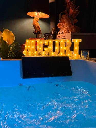 a swimming pool with a lit up sign next to the water at AMA Esclusive SPA Amore in Ferrara