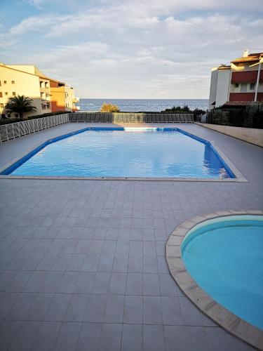 une grande piscine avec l'océan en arrière-plan dans l'établissement Studio cabine idéalement situé vue mer, Les Indes Galantes, piscine, parking, au Cap d'Agde
