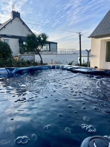 une piscine remplie d'eau en face d'une maison dans l'établissement Le cottage du Lenn, à Louannec