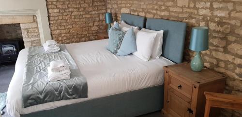 a bed with a blue headboard and pillows on it at The Kings Arms Hotel in Stow on the Wold