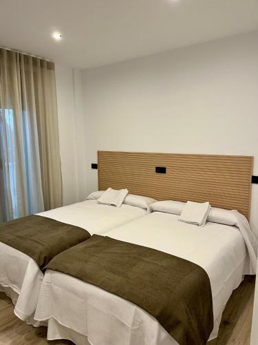 two beds in a hotel room with white sheets at Apartamentos HORNOS in Hornos