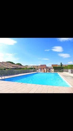 une grande piscine avec un grand bassin bleu dans l'établissement Petite maisonnette de vacances, à Gruissan