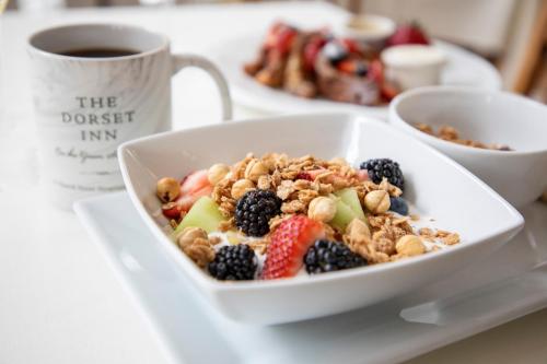 a bowl of fruit and nuts on a plate with a cup of coffee at The Dorset Inn in Dorset