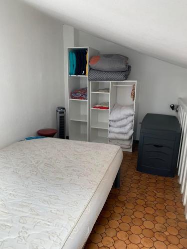 - une chambre avec un lit et des étagères de serviettes dans l'établissement Petite maisonnette de vacances, à Gruissan