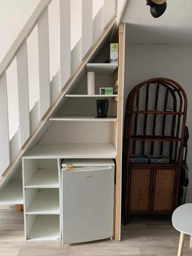 une étagère sous les escaliers avec un réfrigérateur en dessous dans l'établissement Petite maisonnette de vacances, à Gruissan