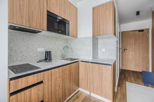 a kitchen with wooden cabinets and a sink at Noli Gdansk Wrzeszcz in Gdańsk