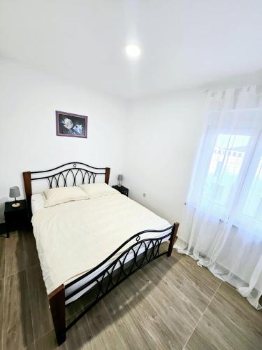 sypialnia z łóżkiem z białą pościelą i zasłonami w obiekcie Apartment Lovre Zadar w mieście Zadar
