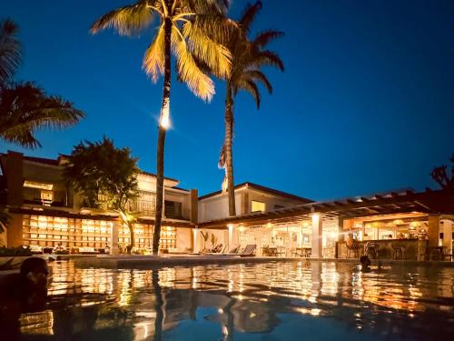 a resort with palm trees and a swimming pool at night at Hotel Premium Recanto da Passagem in Cabo Frio