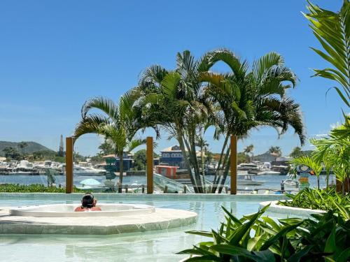 a person swimming in a pool with palm trees at Hotel Premium Recanto da Passagem in Cabo Frio