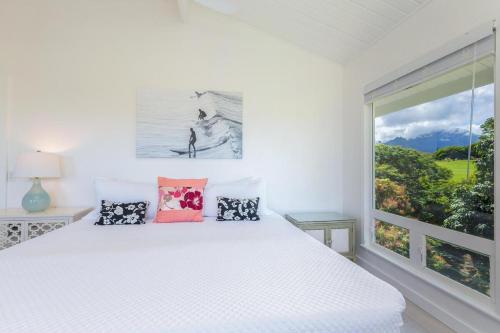 a bedroom with a white bed and a large window at Hale Mauna Nui in Princeville