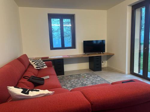 a living room with a red couch and a desk at Villa panoramica sulle colline del Monferrato in Calamandrana