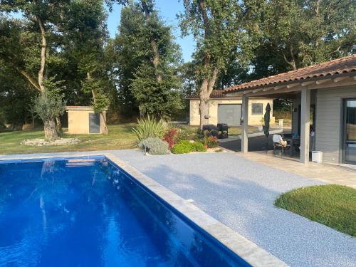 une piscine bleue devant une maison dans l'établissement Maison de campagne atypique, à Monfort