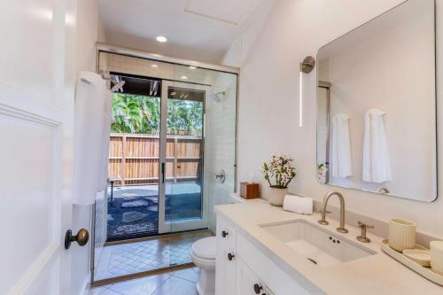 a white bathroom with a sink and a mirror at Hale Nanea in Kilauea