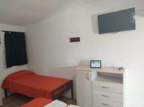 Un dormitorio con una cama, una cómoda y un televisor. en El Tata, en Recreo