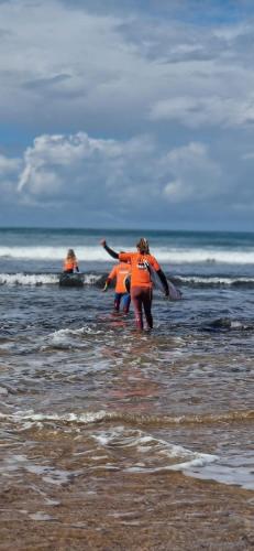 a group of people walking in the water at the beach at Imsouane petitsurfer SurfCamp in Imsouane