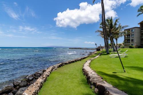 a beach with palm trees and a building and the ocean at Maalaea Kai 315 in Wailuku