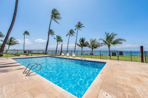 a swimming pool with palm trees and the ocean at Maalaea Kai 315 in Wailuku