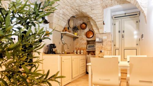 a kitchen with white cabinets and a stone wall at Dimora Fiore Guest House in Martina Franca