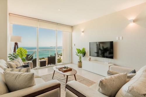 a living room with white furniture and a large window at MAREA New 2 BDR Beachfront by Casa Paraíso in Cancún