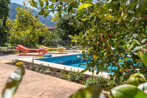 a swimming pool with two red chairs next to it at Finca Xesca in Sóller