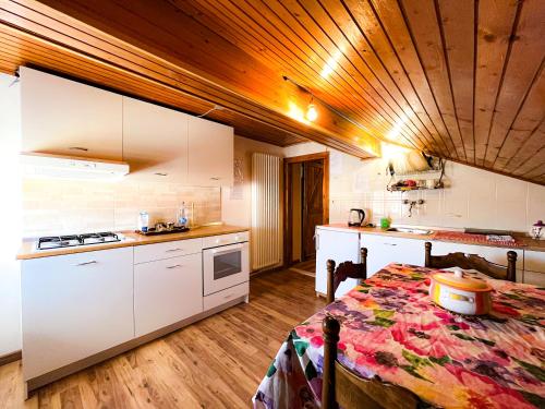 a kitchen with white cabinets and a table in a room at La casa di Leo in Folgaria