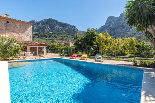 a swimming pool in front of a house with mountains at Finca Xesca in Sóller