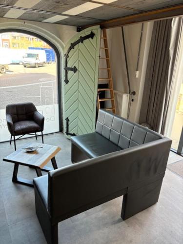a living room with a couch and a chair and a table at De Oude Brandweerkazerne 2 tot 4 persoons 2 kamer appartement in Kaatsheuvel