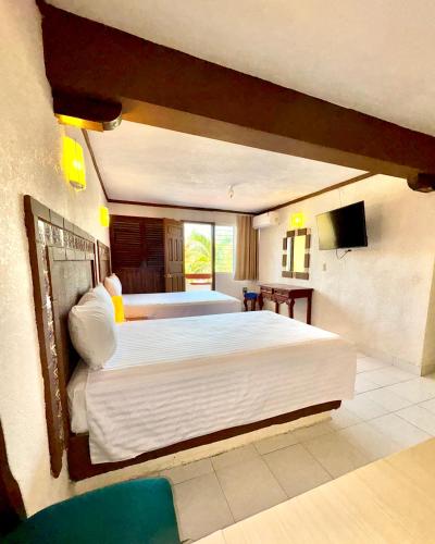 a bedroom with two beds and a flat screen tv at Suites Cancun Center in Cancún