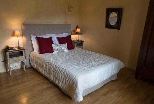a bedroom with a large bed with red pillows at Logis Hôtel Les Hospitaliers in Le Poët-Laval