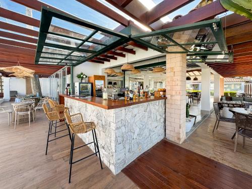 a restaurant with a bar with chairs and tables at Hotel Premium Recanto da Passagem in Cabo Frio