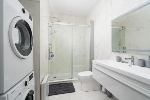 a white bathroom with a shower and a washing machine at The S&D Apartments in Montréal