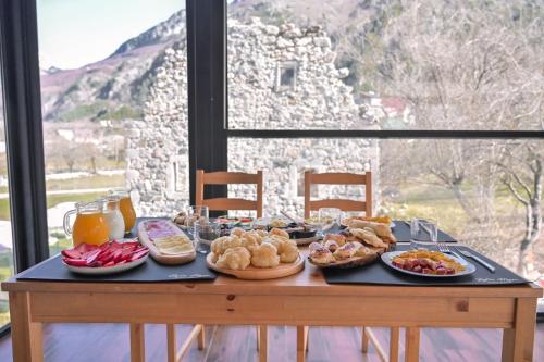 a table with plates of food on it with a window at Bujtina Miqesia in Theth