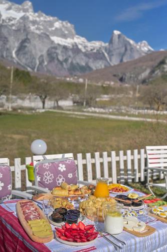 a table with food on it with mountains in the background at Bujtina Miqesia in Theth