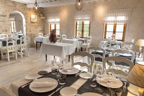 a dining room with white tables and white chairs at Logis Hôtel Les Hospitaliers in Le Poët-Laval