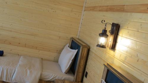 a room with a wooden wall with a bed and a light at Cottage nikolozi2 in Arsha