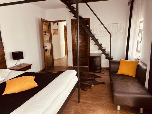a bedroom with a bed and a couch and a staircase at Casa Pisica Noastra in Breaza