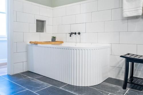 a bath tub in a bathroom with white tiles at New Remodel! 4BR Near DT Cartersville & Major Hwys in Cartersville
