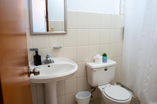 a bathroom with a toilet and a sink and a mirror at Ocean Village at Combate in Cabo Rojo