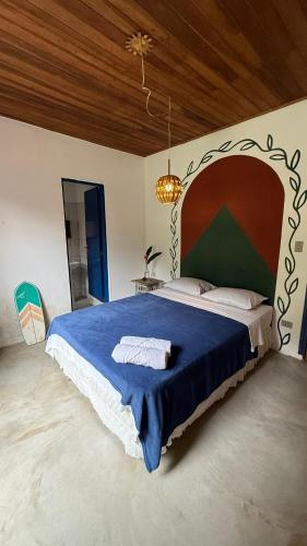 a bedroom with a large bed with a blue blanket at Sambaqui Hostel in Ilhabela