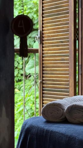 a window with a blue table with two towels on it at Sambaqui Hostel in Ilhabela