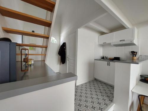 une cuisine avec des placards blancs et un comptoir gris dans l'établissement L'ermitage du gué - Cocon paisible avec extérieur, à La Rochelle