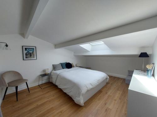 une chambre avec un lit blanc et une lucarne dans l'établissement L'ermitage du gué - Cocon paisible avec extérieur, à La Rochelle