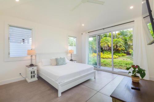 a white bedroom with a bed and a large window at Tradewinds in Princeville