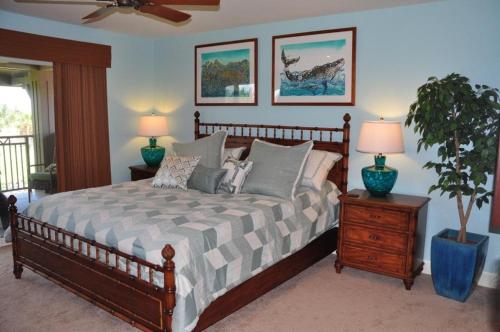 ein Schlafzimmer mit einem Bett mit zwei Lampen und einer Topfpflanze in der Unterkunft Halii Kai 9G in Waikoloa