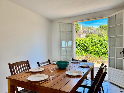 une table de salle à manger avec des chaises et une grande fenêtre dans l'établissement Grand Duplex - Terrasse Vue Mer, à Carqueiranne