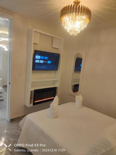 a bedroom with a bed and a tv and a chandelier at Aparta Hotel Boutique Salento in Salento