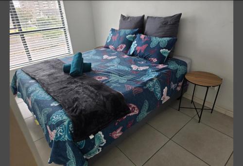 开普敦Sunset at Keys的一张带蓝色棉被和一张桌子的床